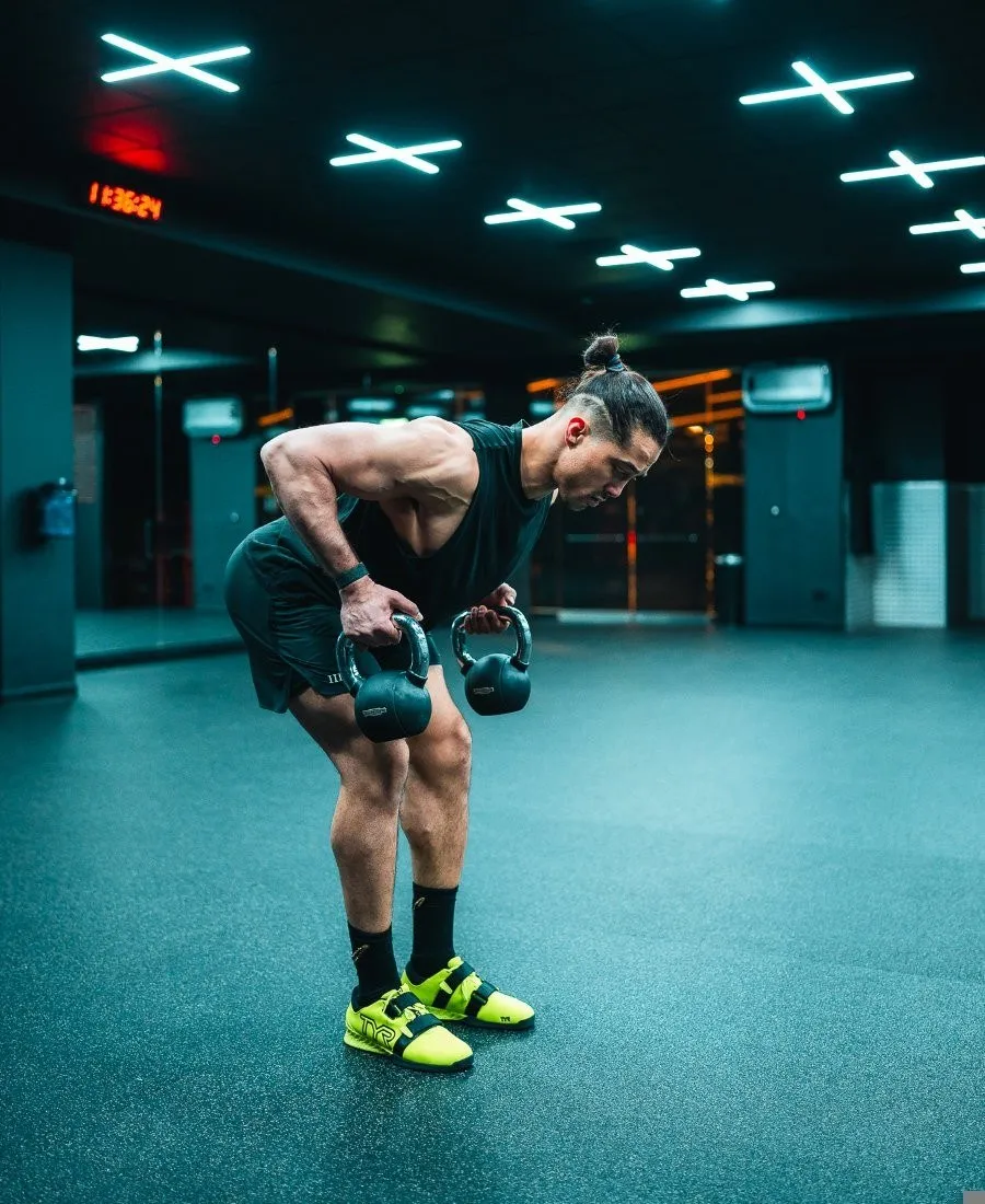 Moe in a double kettlebell row in a dark gym, in black and white